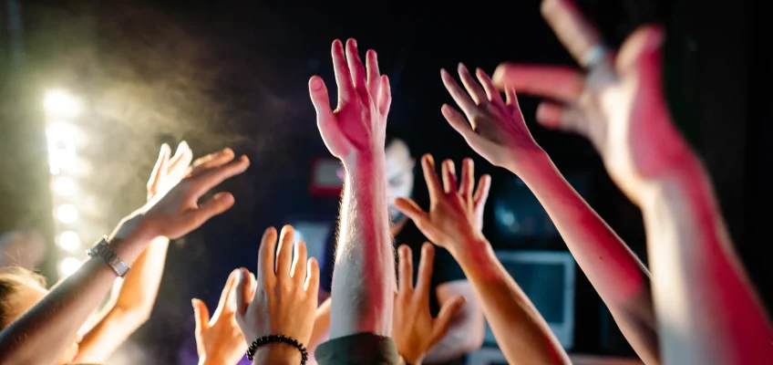 Picture of peoples hands in the air to illustrate dancing to the perfect birthday party playlist.